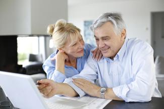 Elderly couple looking at a computer and smiling